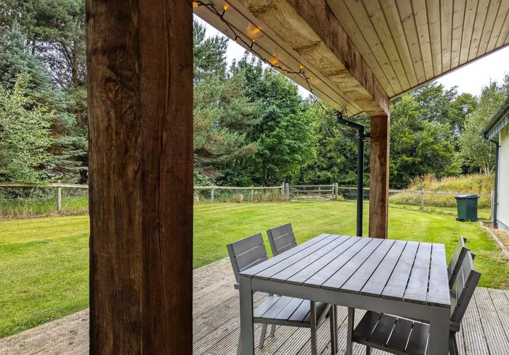 a picnic table and chairs on a porch with a field at Logies Croft in Kellas