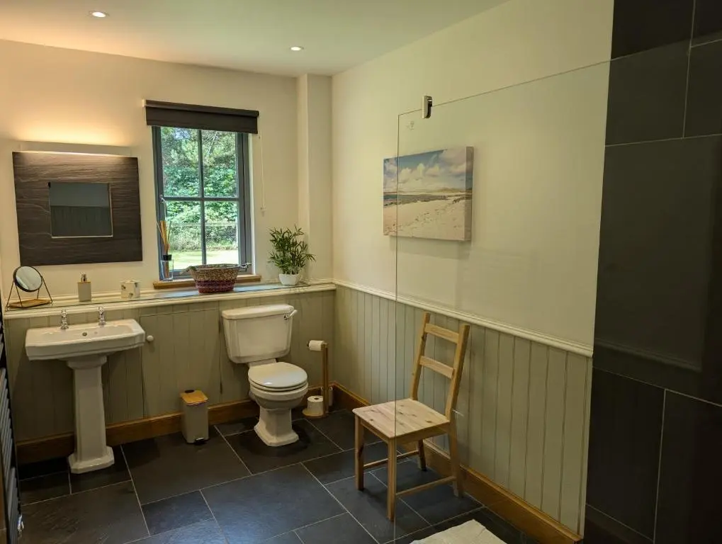 a bathroom with a toilet and a sink and a chair at Logies Croft in Kellas
