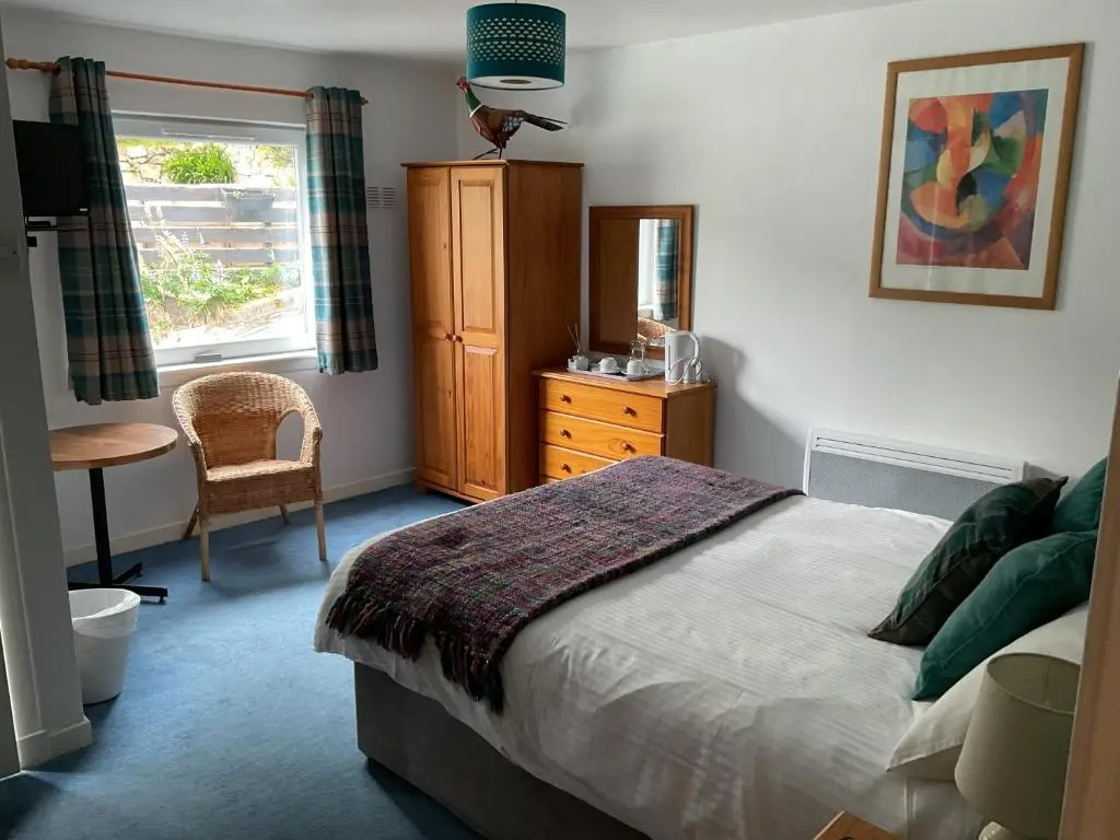 a bedroom with a bed and a dresser and a window at The Castle Hotel NR TAIN in Portmahomack