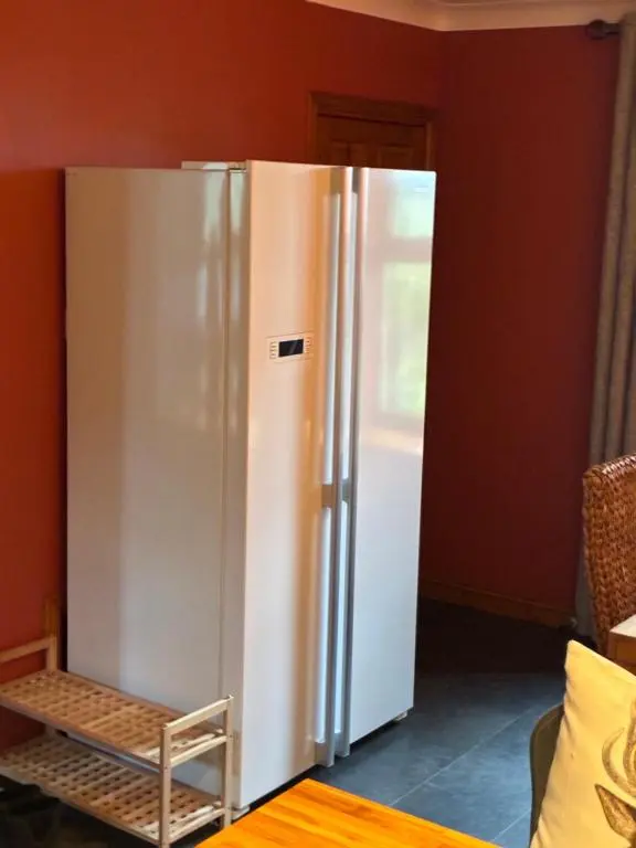a refrigerator in a room with a red wall at Cottage Farmhouse in Huntly