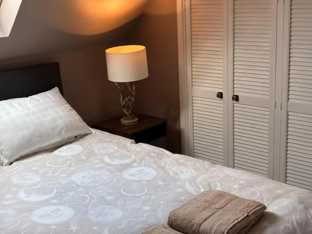a bedroom with a bed with a pillow and a lamp at Cottage Farmhouse in Huntly