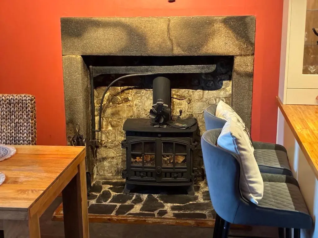 a stone fireplace with a stove in a room at Cottage Farmhouse in Huntly