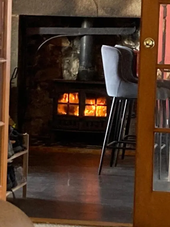 a room with a fireplace with two chairs in front of it at Cottage Farmhouse in Huntly