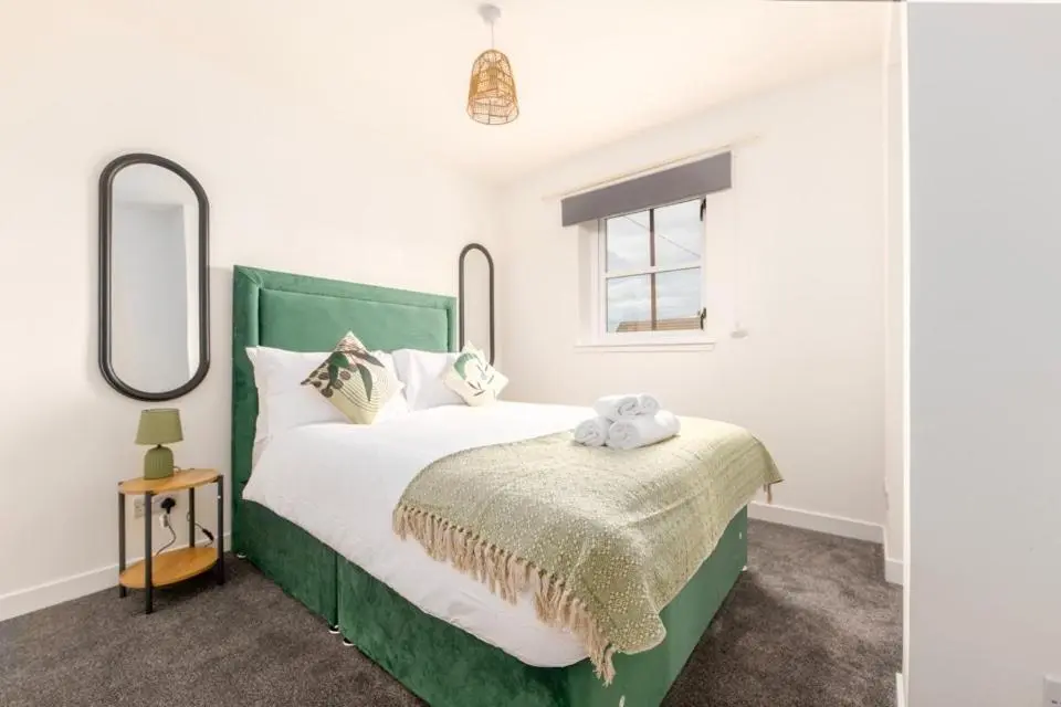a bedroom with a green bed with two mirrors at 1 BDR Apartment At Caledonia Luxe Stays Short Lets & Serviced Accommodation Inverness in Inverness