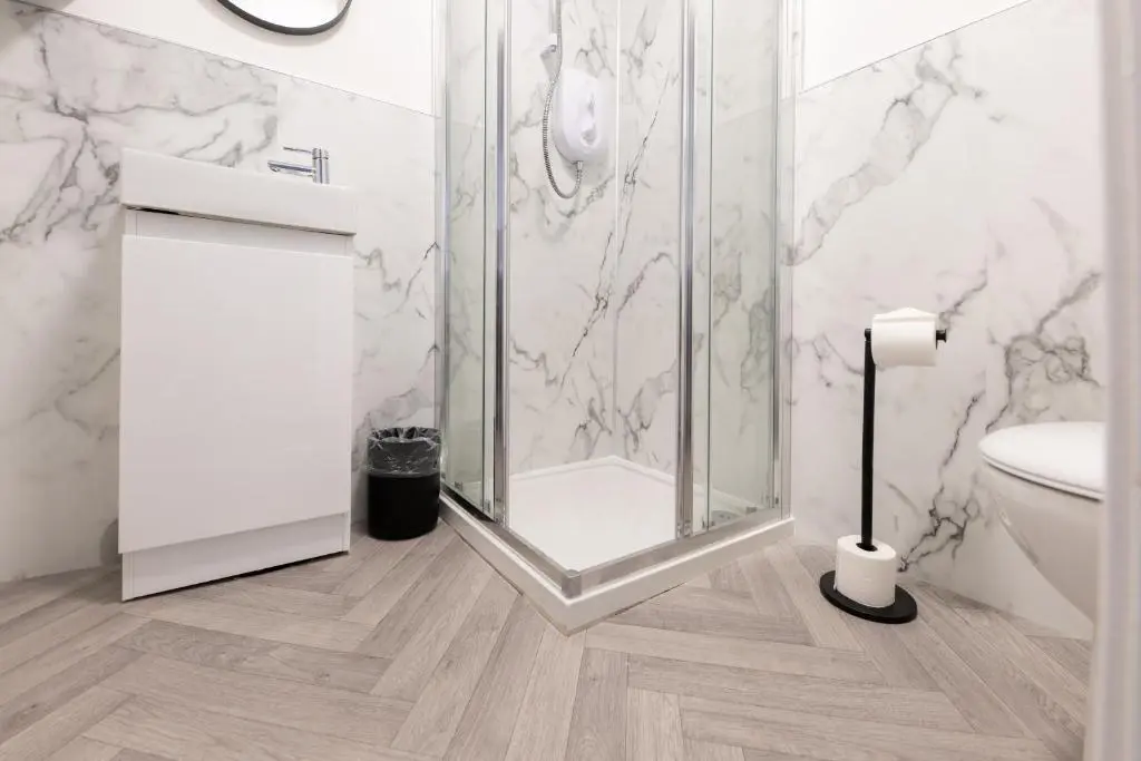 a bathroom with a shower with a toilet and a sink at Dram Apartment in Inverness