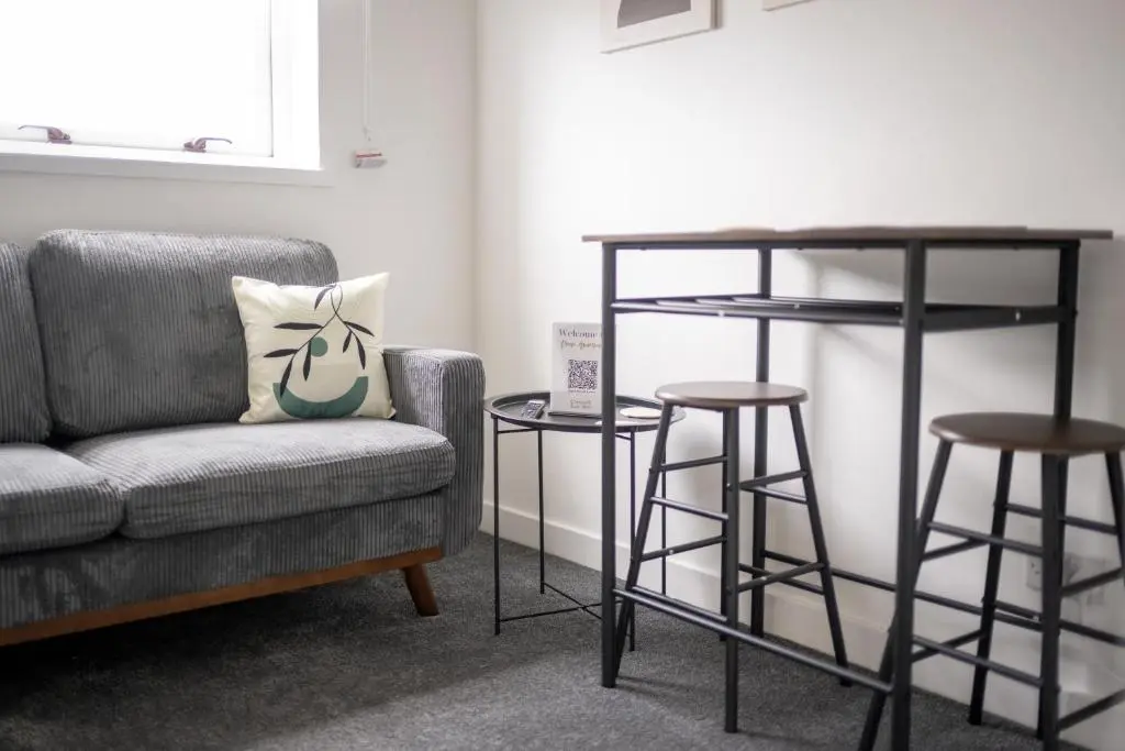 a living room with a couch and two bar stools at Dram Apartment in Inverness