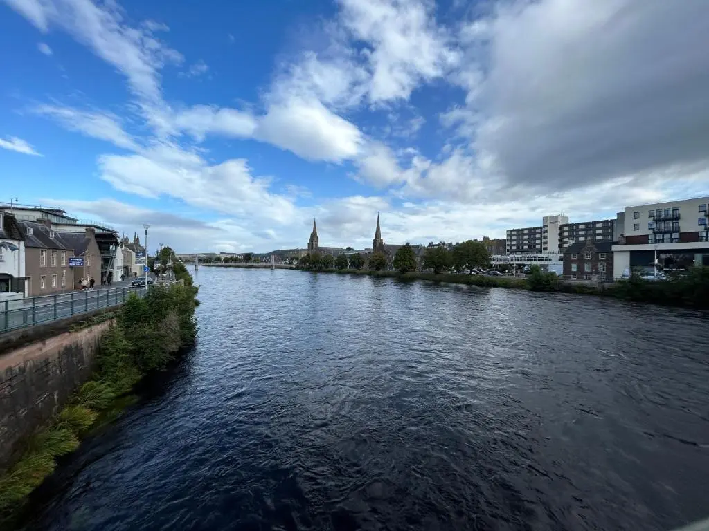 a river in a city with buildings and a blue sky at Cosy Flat Close to City Centre Ideal for Families in Dalneigh