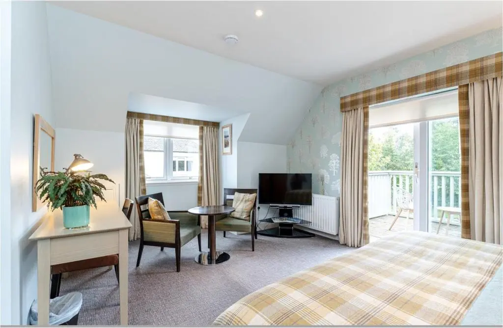 a bedroom with a bed and a desk and a television at Sandown House in Nairn