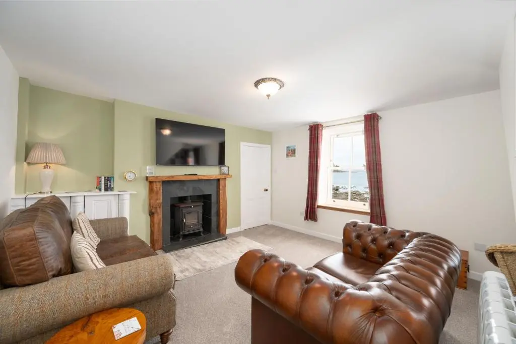 a living room with a couch and a fireplace at Soundwaves, Seatown, Gardenstown in Gardenstown