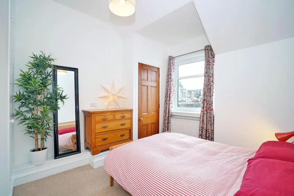 a bedroom with a bed and a dresser and a window at Bright and cosy central flat in Inverurie in Inverurie