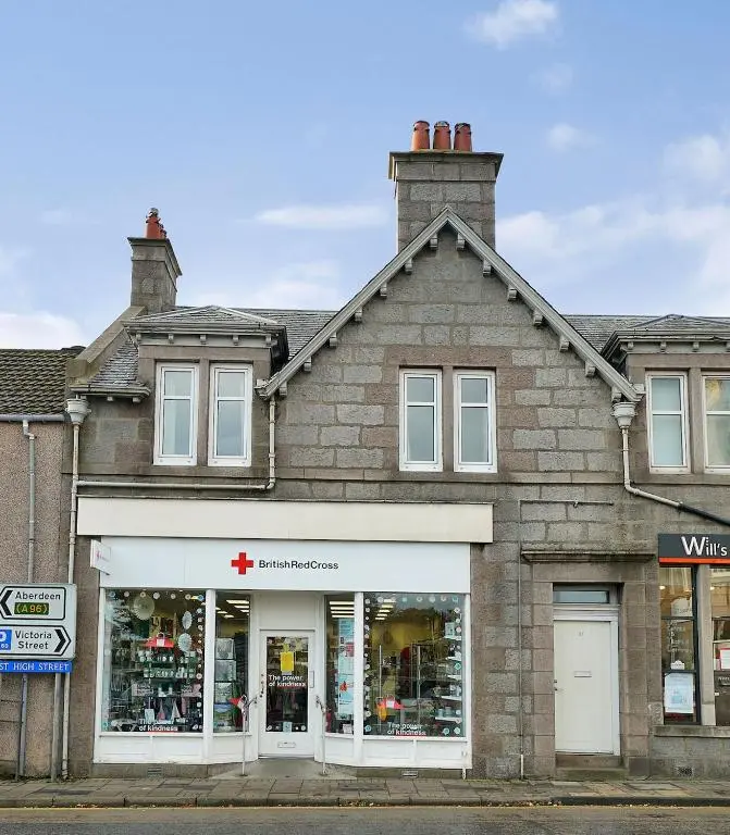 a store front of a brick building with a pharmacy at Bright and cosy central flat in Inverurie in Inverurie