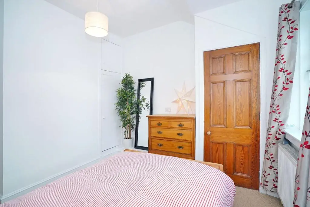 a bedroom with a bed and a wooden door at Bright and cosy central flat in Inverurie in Inverurie