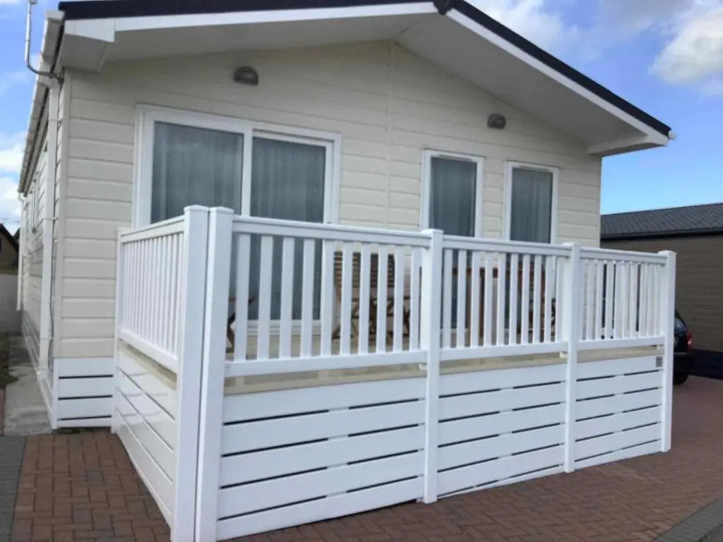 a small white house with a white fence at Parkview holiday lodge in Lossiemouth