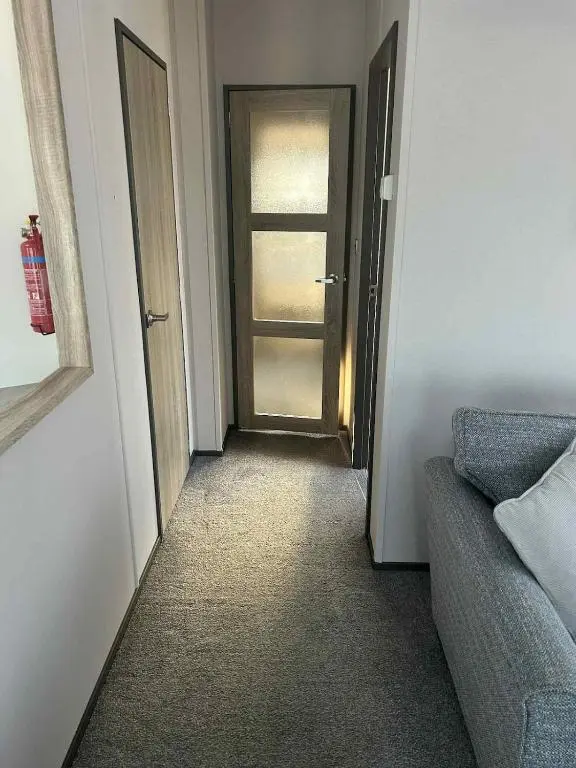 a hallway with a door and a couch in a room at Parkview holiday lodge in Lossiemouth