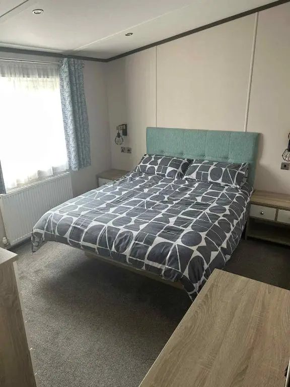 a bedroom with a bed with a black and white comforter at Parkview holiday lodge in Lossiemouth