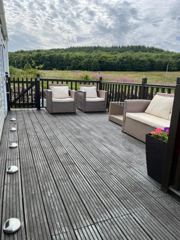 a deck with couches and chairs on a house at Number 28 Dornoch Firth Caravan Park in Dornoch