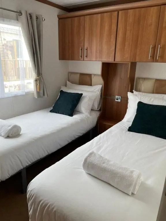 two beds in a room with a towel on the bed at Number 28 Dornoch Firth Caravan Park in Dornoch
