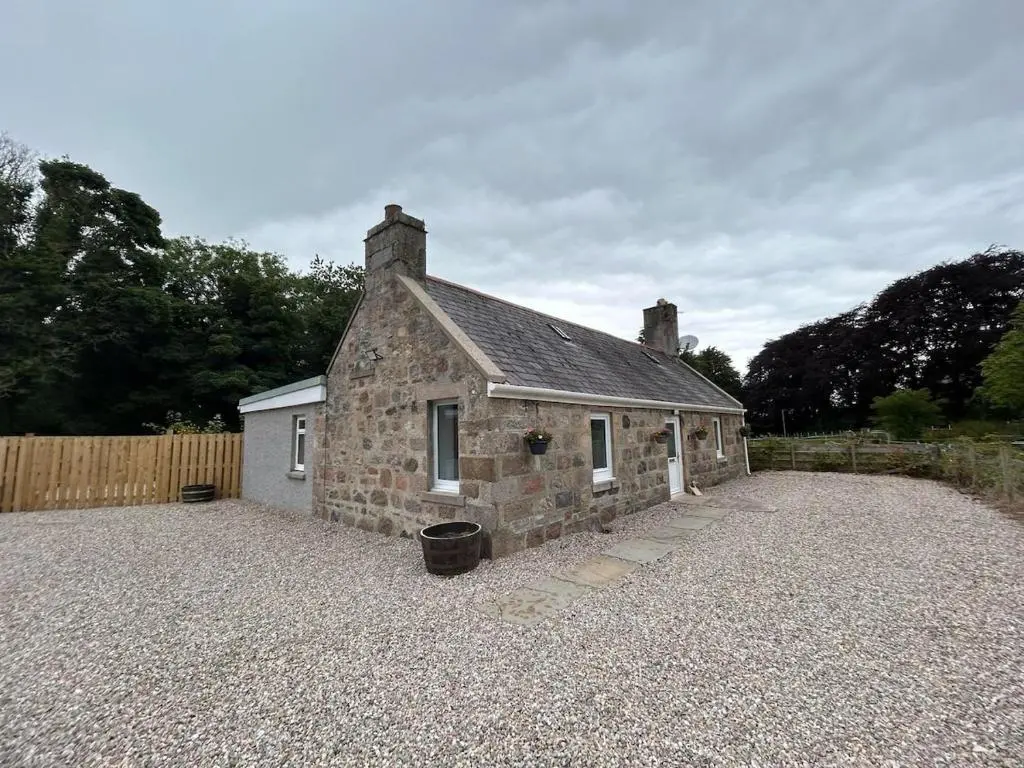 an old stone house with a gravel driveway at Burnside Cottage in Fochabers
