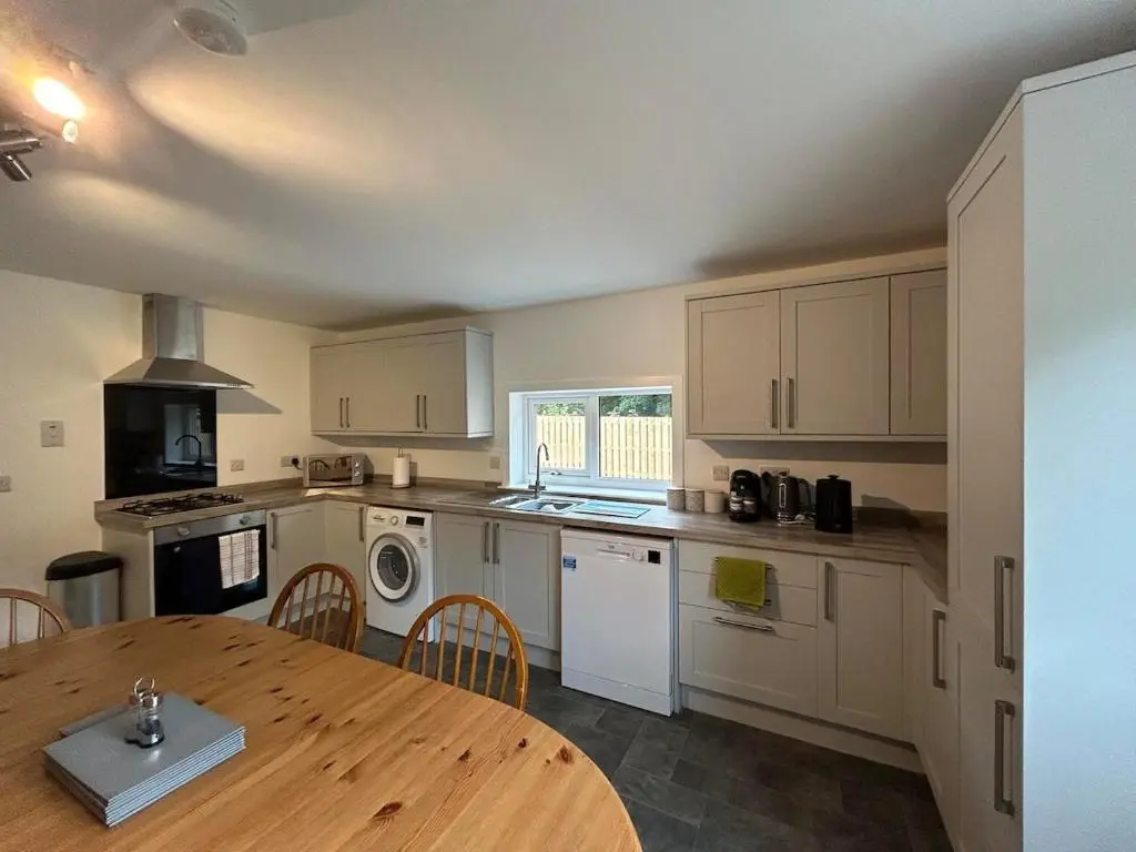 a kitchen with a wooden table and a dining room at Burnside Cottage in Fochabers