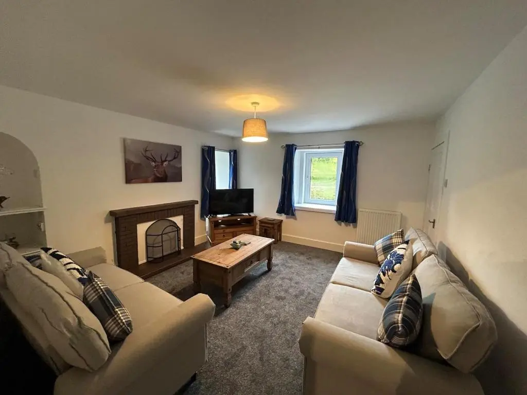 a living room with two couches and a fireplace at Burnside Cottage in Fochabers