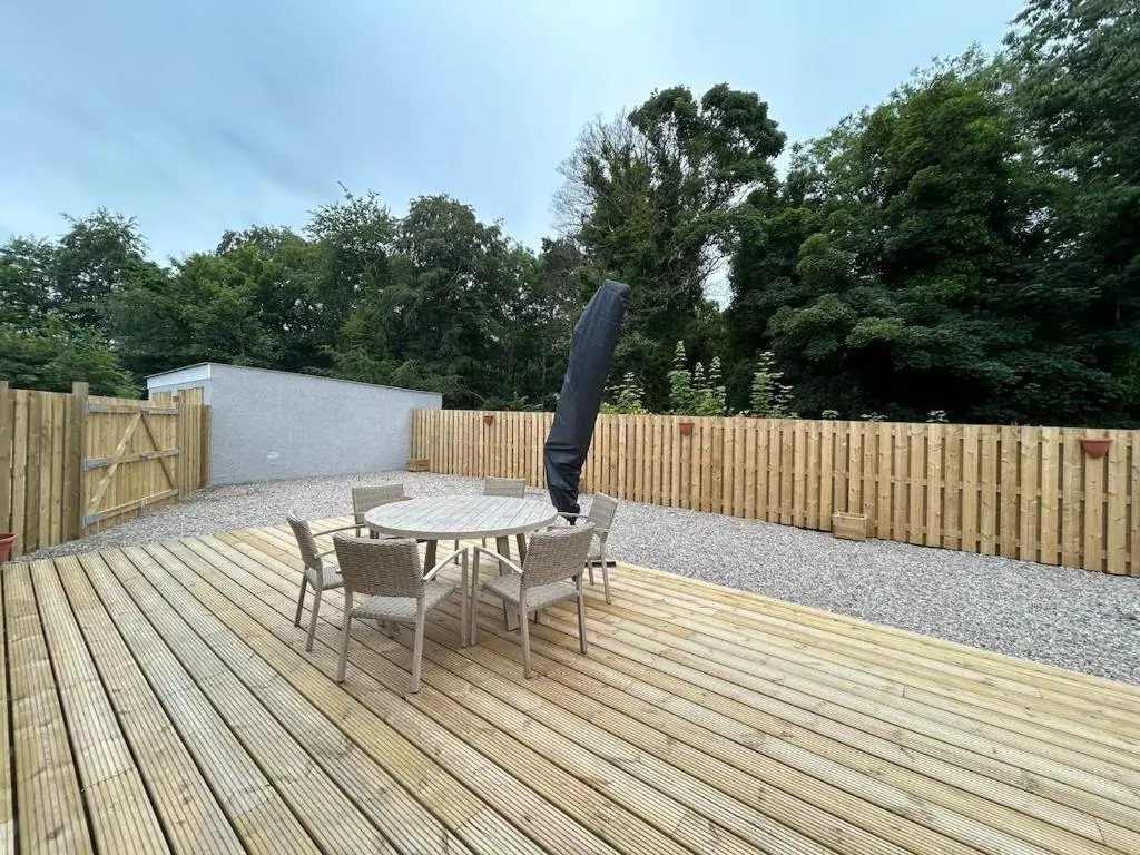 a patio with an umbrella and a table and chairs at Burnside Cottage in Fochabers