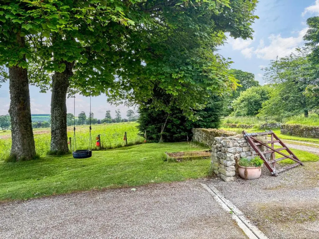 a garden with a gate and a stone wall at The Cottage At Mains House in Tain