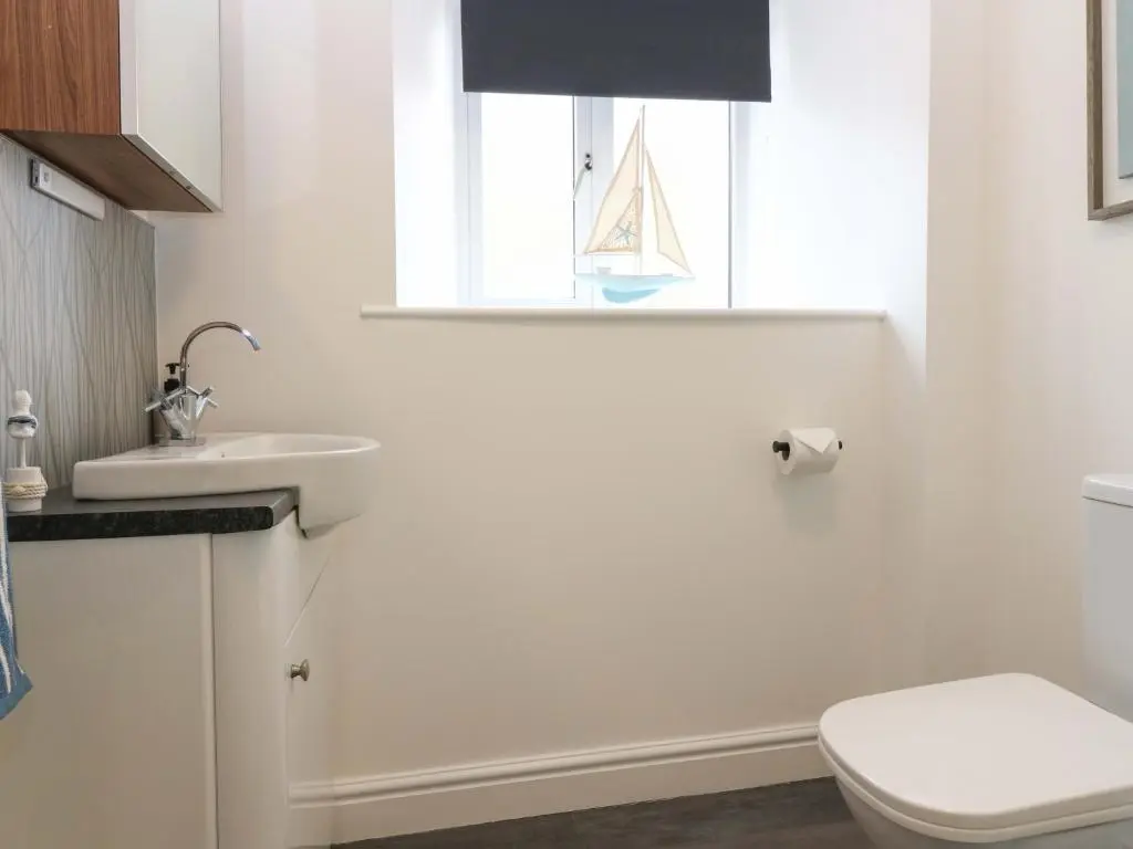 a bathroom with a toilet and a sink and a window at 3 Caroline Place in Fraserburgh