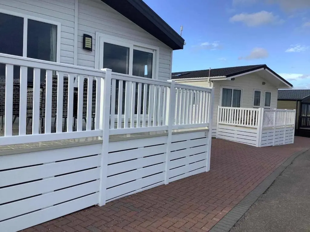 a white fence in front of a house at Clearwater Lodge in Lossiemouth