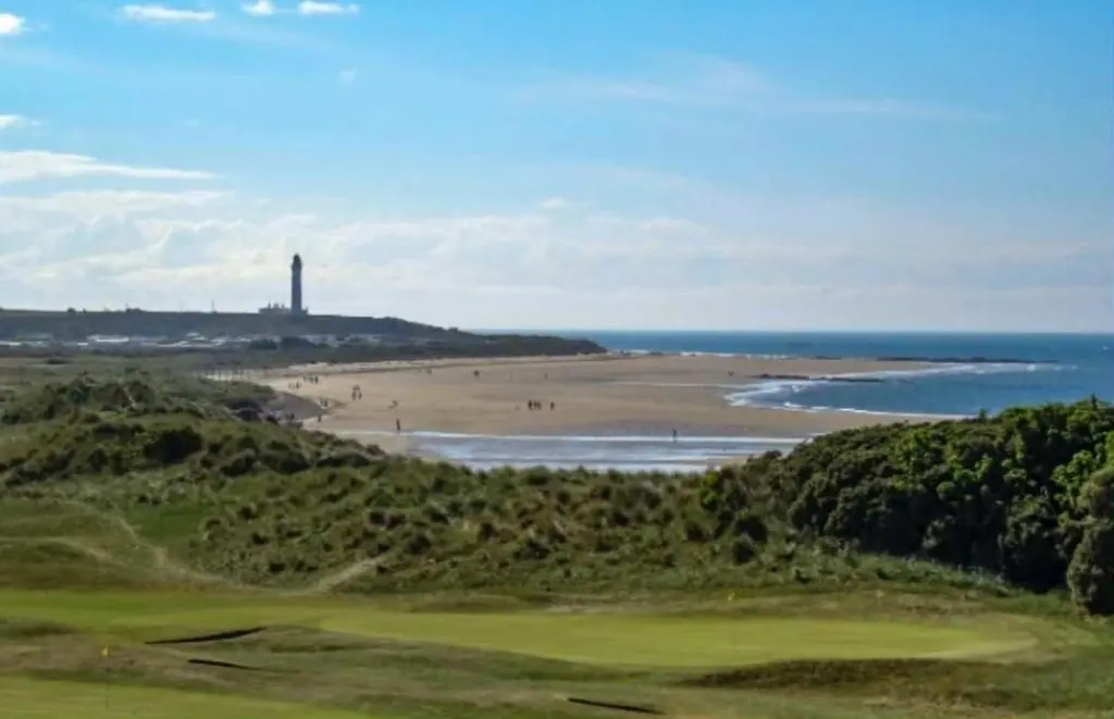 a view of a beach with a lighthouse in the distance at Clearwater Lodge in Lossiemouth