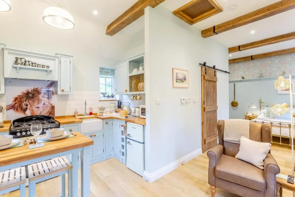 a kitchen with white cabinets and a table and a chair at 1 Bed in Drumnadrochit oc-t32404 in Drumnadrochit