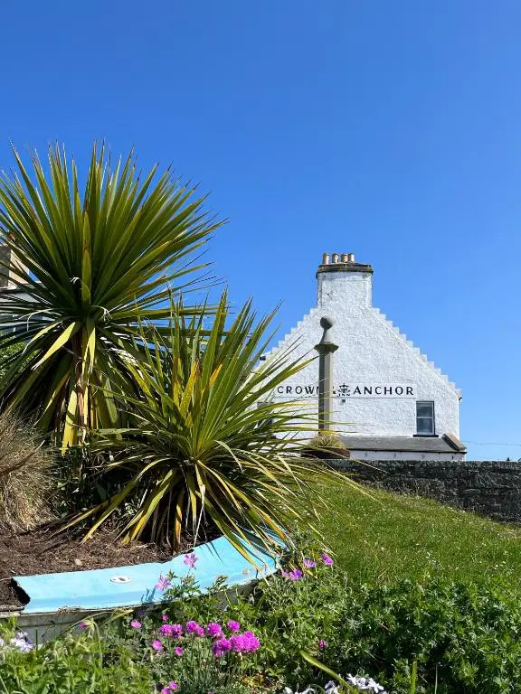 a lighthouse on top of a hill with plants and flowers at Crown and Anchor Inn in Findhorn
