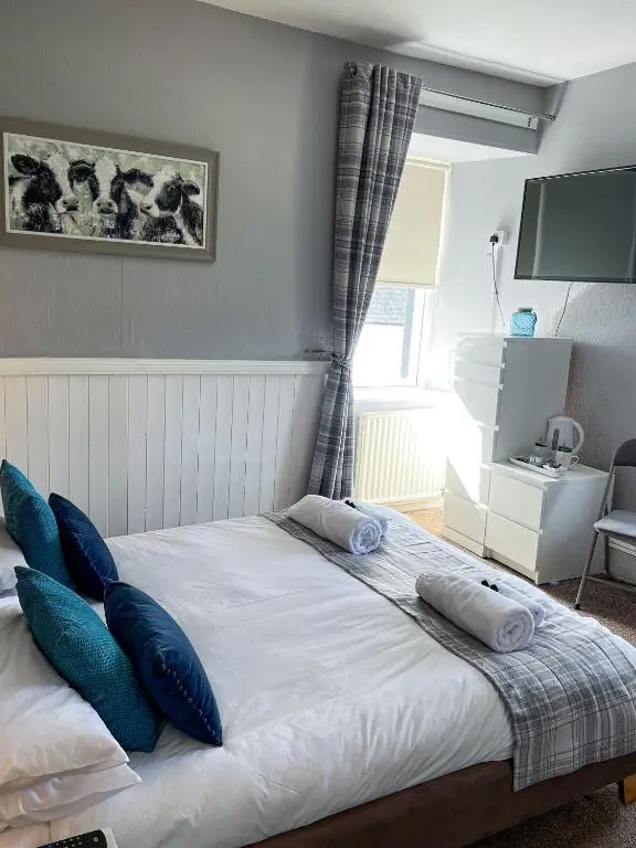 a bedroom with a bed with blue pillows on it at Crown and Anchor Inn in Findhorn