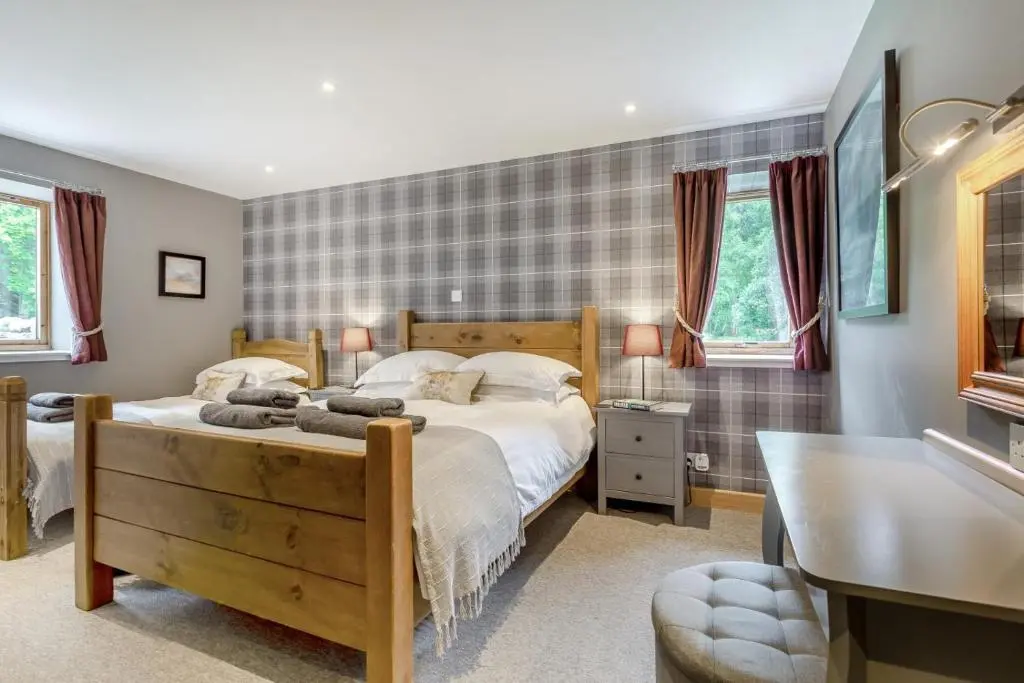 a bedroom with a bed and a desk and windows at 1 Bed in Newtonmore oc-c32414 in Newtonmore