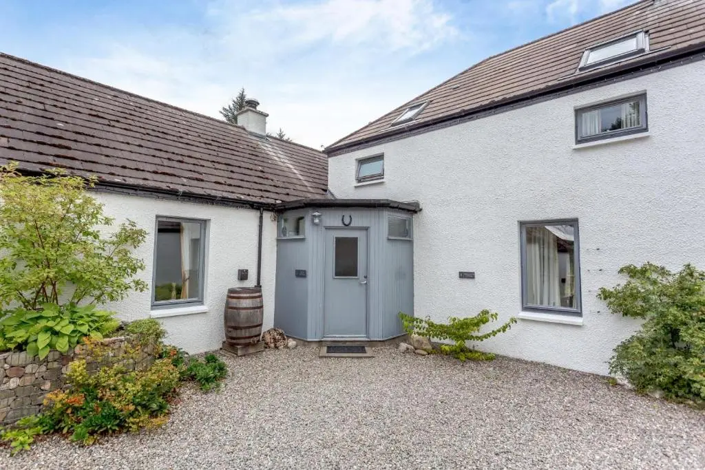 a white house with a gray door and a yard at 1 Bed in Newtonmore oc-c32414 in Newtonmore