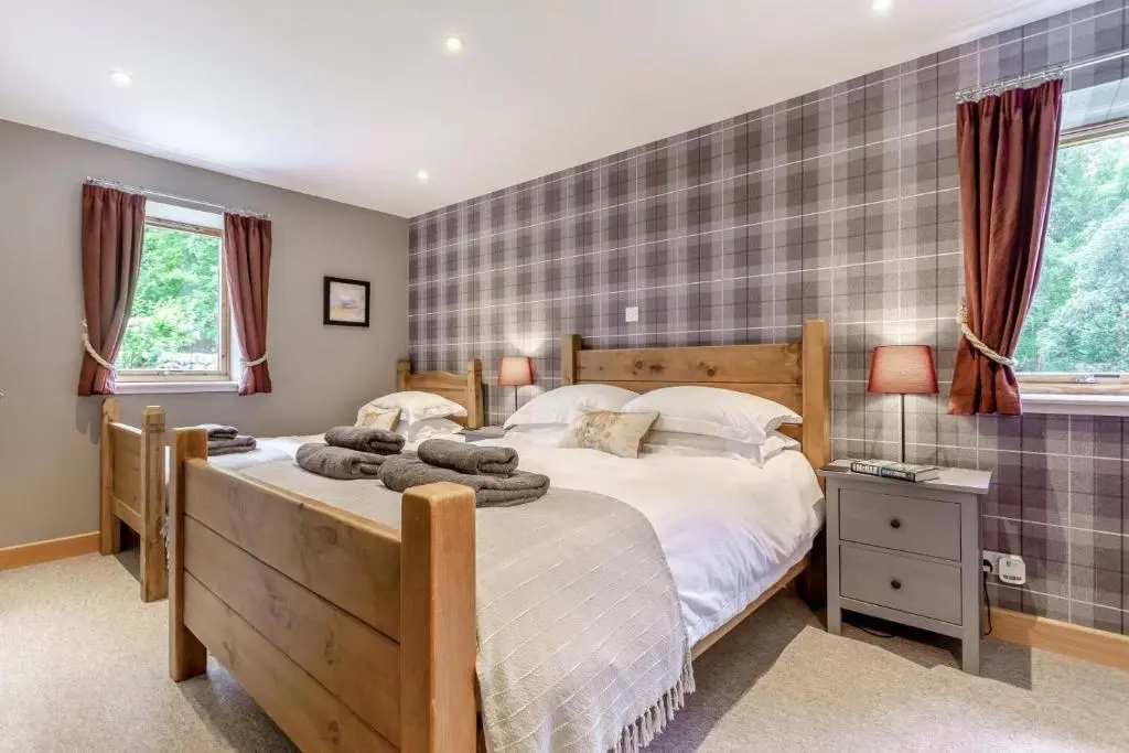 a bedroom with a large bed and two windows at 1 Bed in Newtonmore oc-c32414 in Newtonmore