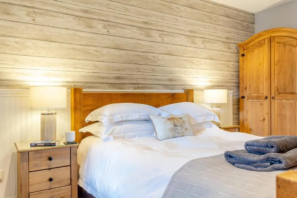 a bedroom with a large bed with a wooden wall at 1 Bed in Newtonmore oc-l32415 in Newtonmore