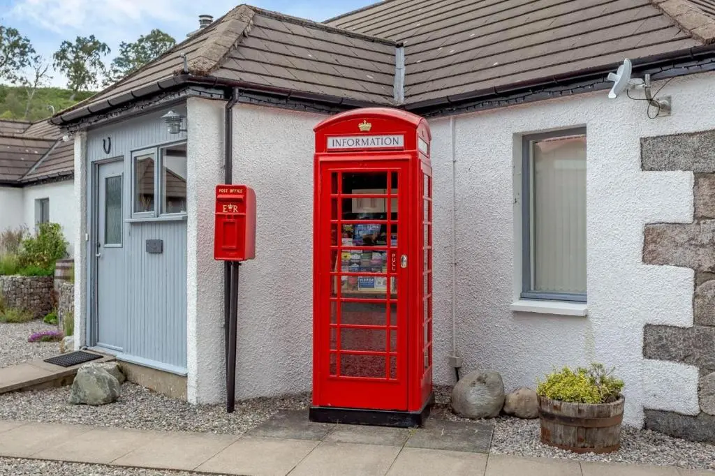 an old red phone booth in front of a house at 1 Bed in Newtonmore oc-b32417 in Newtonmore