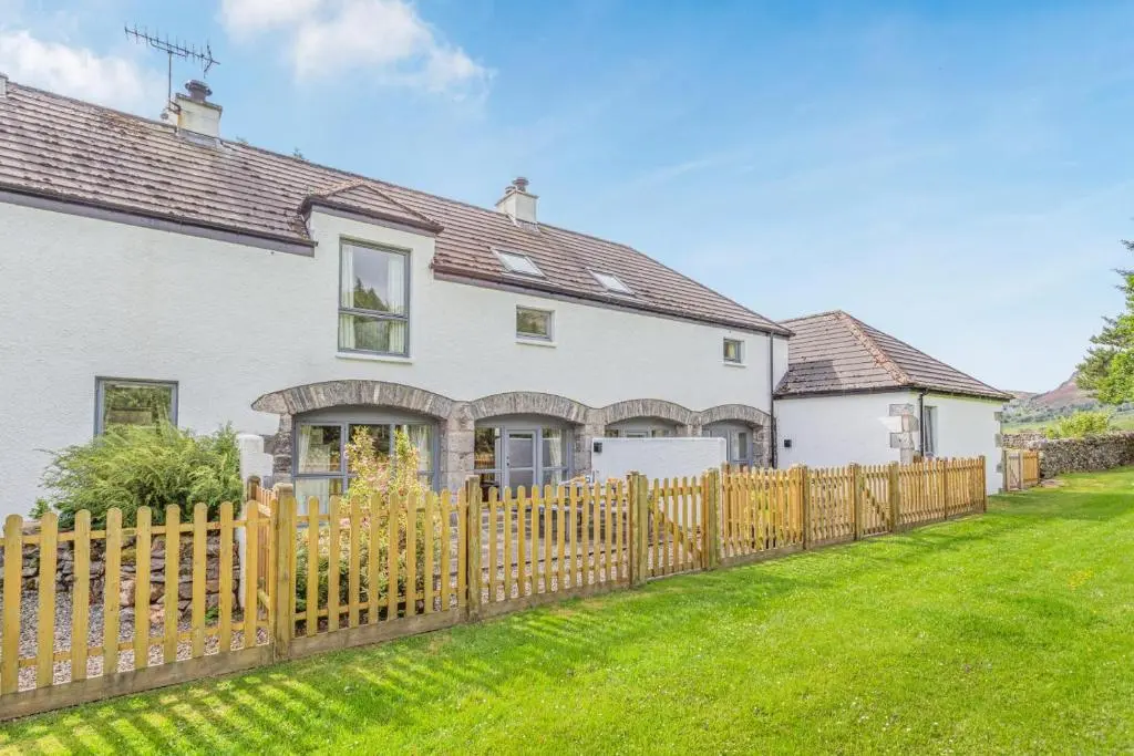 a white house with a wooden fence at 2 Bed in Newtonmore oc-e32418 in Newtonmore