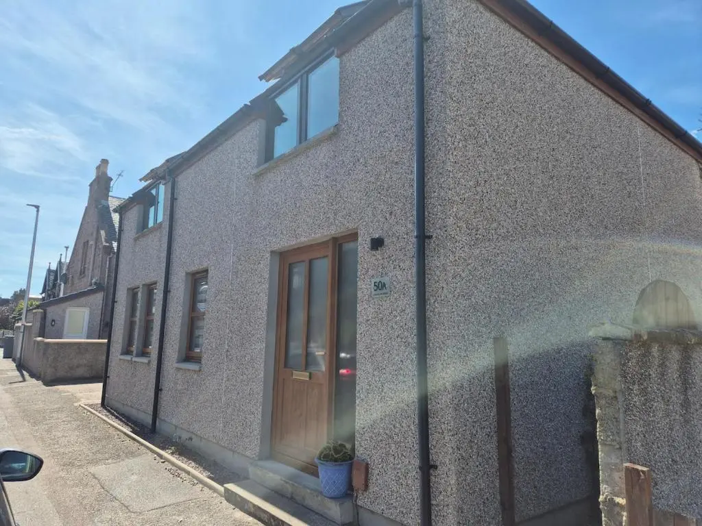 a brick building with a wooden door on a street at 2 Bed House - free parking, short walk to City centre in Inverness