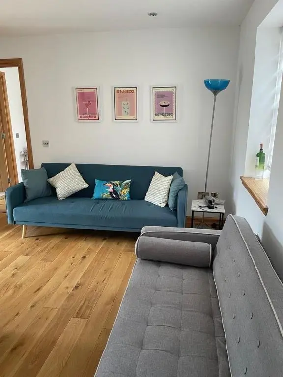 a living room with a blue couch and wooden floors at 2 Bed House - free parking, short walk to City centre in Inverness