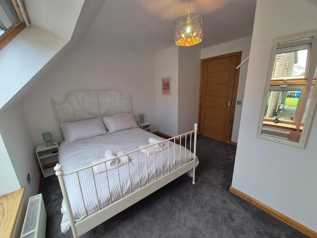 a bedroom with a crib in a room with a window at 2 Bed House - free parking, short walk to City centre in Inverness