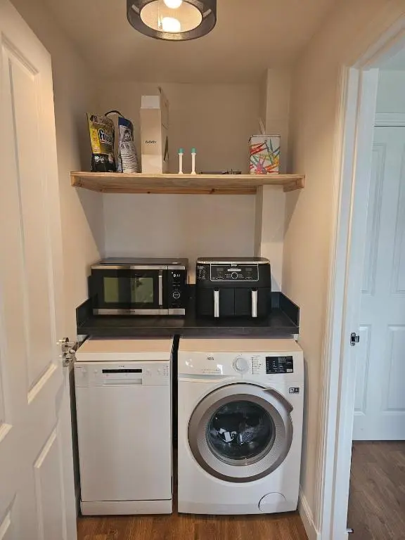 a laundry room with a washing machine and a microwave at City and Loch Ness Blend in Inverness
