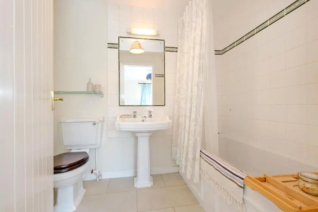 a bathroom with a sink and a toilet and a mirror at Finest Retreats - Corrennie School Cottage in Inverurie