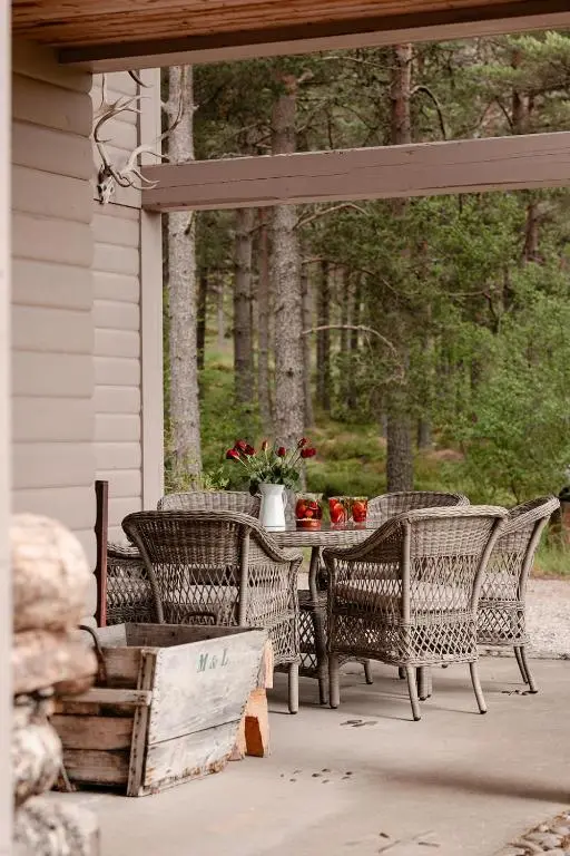 a patio with chairs and a table with flowers at Glencarnie - Seasgair Lodges in Boat of Garten
