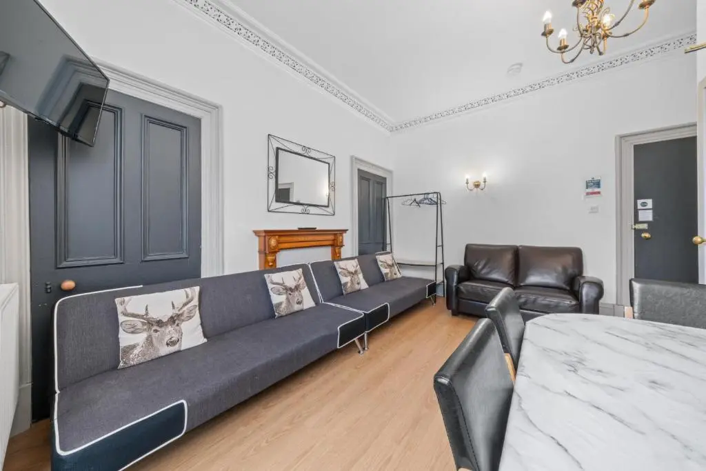 a living room with a black couch and a piano at Central Inverness Hideaway - 2 Bedroom Flat in Inverness