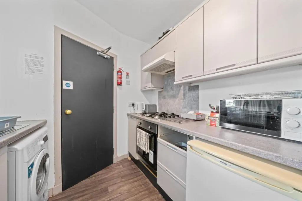 a kitchen with white cabinets and a black door at Central Inverness Hideaway - 2 Bedroom Flat in Inverness