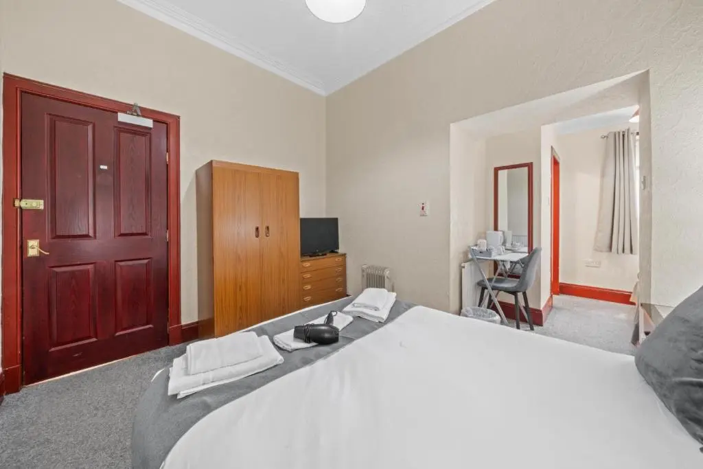 a bedroom with a large bed with a red door at Struy Guest House - Inverness in Inverness