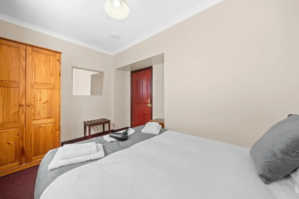 a bedroom with a large white bed and a wooden cabinet at Struy Guest House - Inverness in Inverness