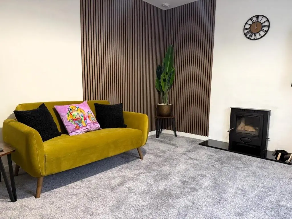 a yellow couch in a living room with a fireplace at Meadowside-Stylish Newly Renovated 2 bed property in Insch
