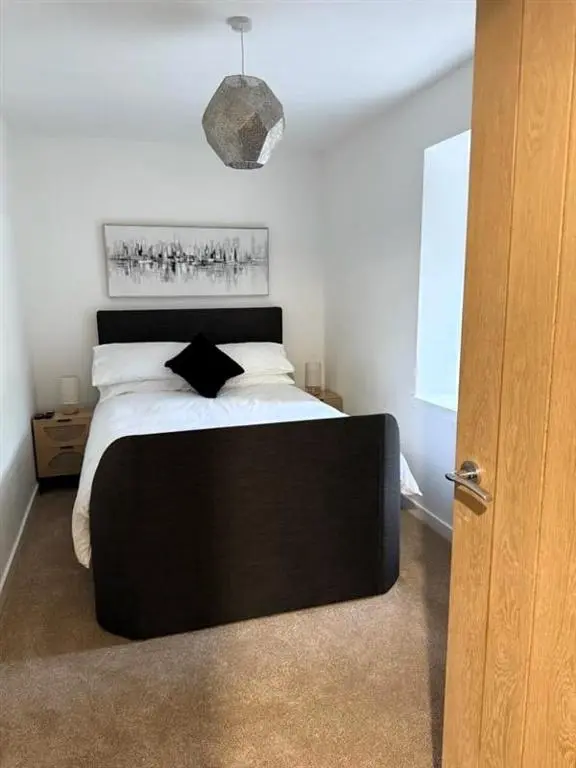 a bedroom with a large bed with a black headboard at Meadowside-Stylish Newly Renovated 2 bed property in Insch